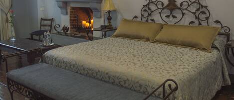 A neatly arranged bedroom with a bed, bedside table, lamp, and a fireplace.