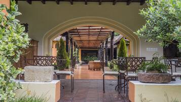 Relax in a tranquil outdoor space with tables, chairs, and a stone bench under a covered pergola.