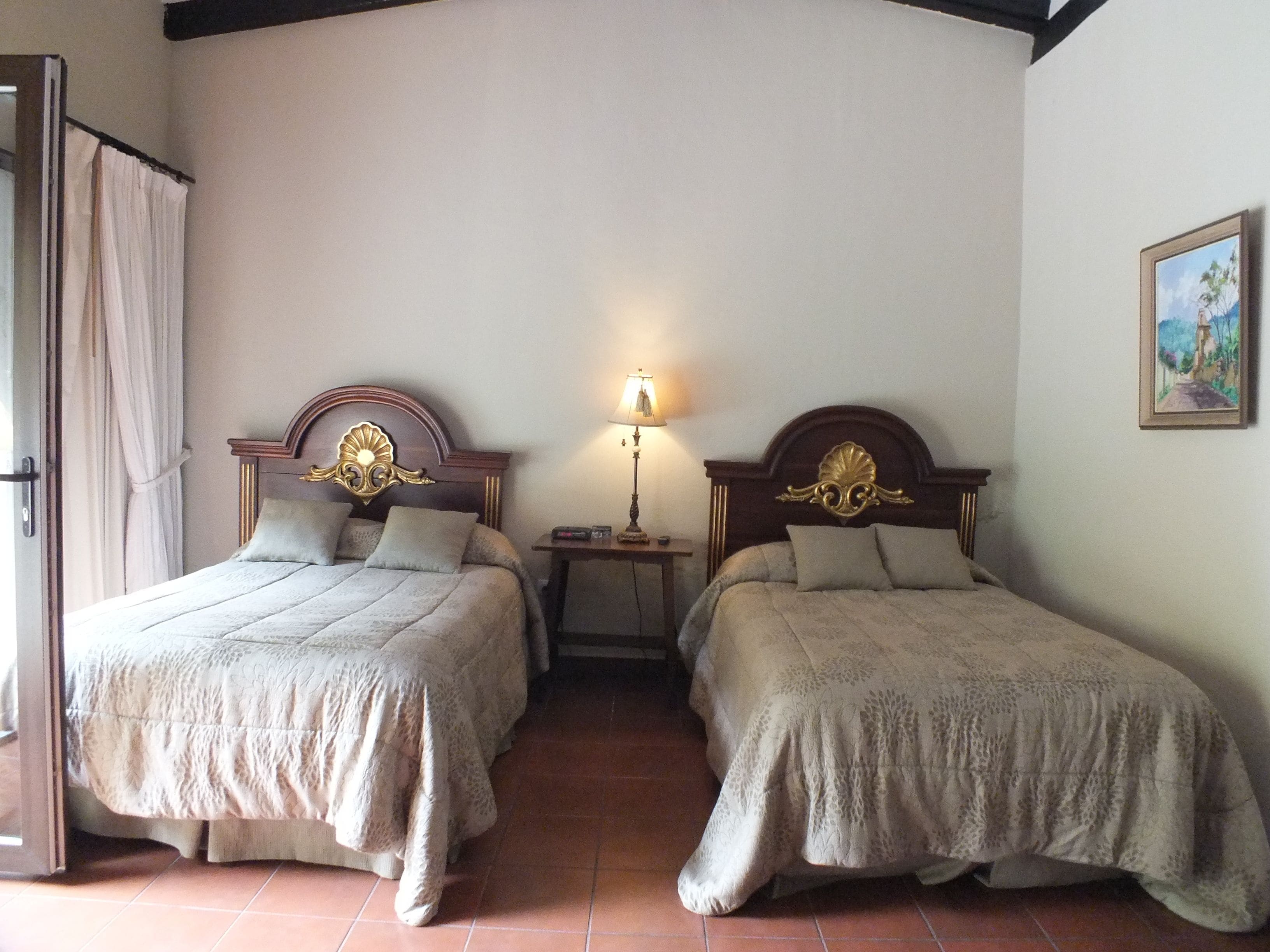 Une chambre avec deux lits, chacun doté d’une tête de lit en bois et d’une lampe sur une table de chevet.