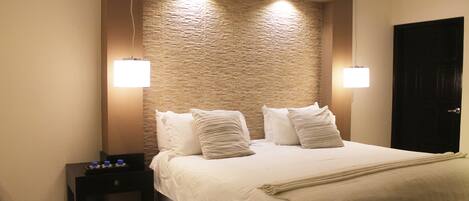 Una habitación de hotel con una cama grande, dos mesitas de noche y una puerta.