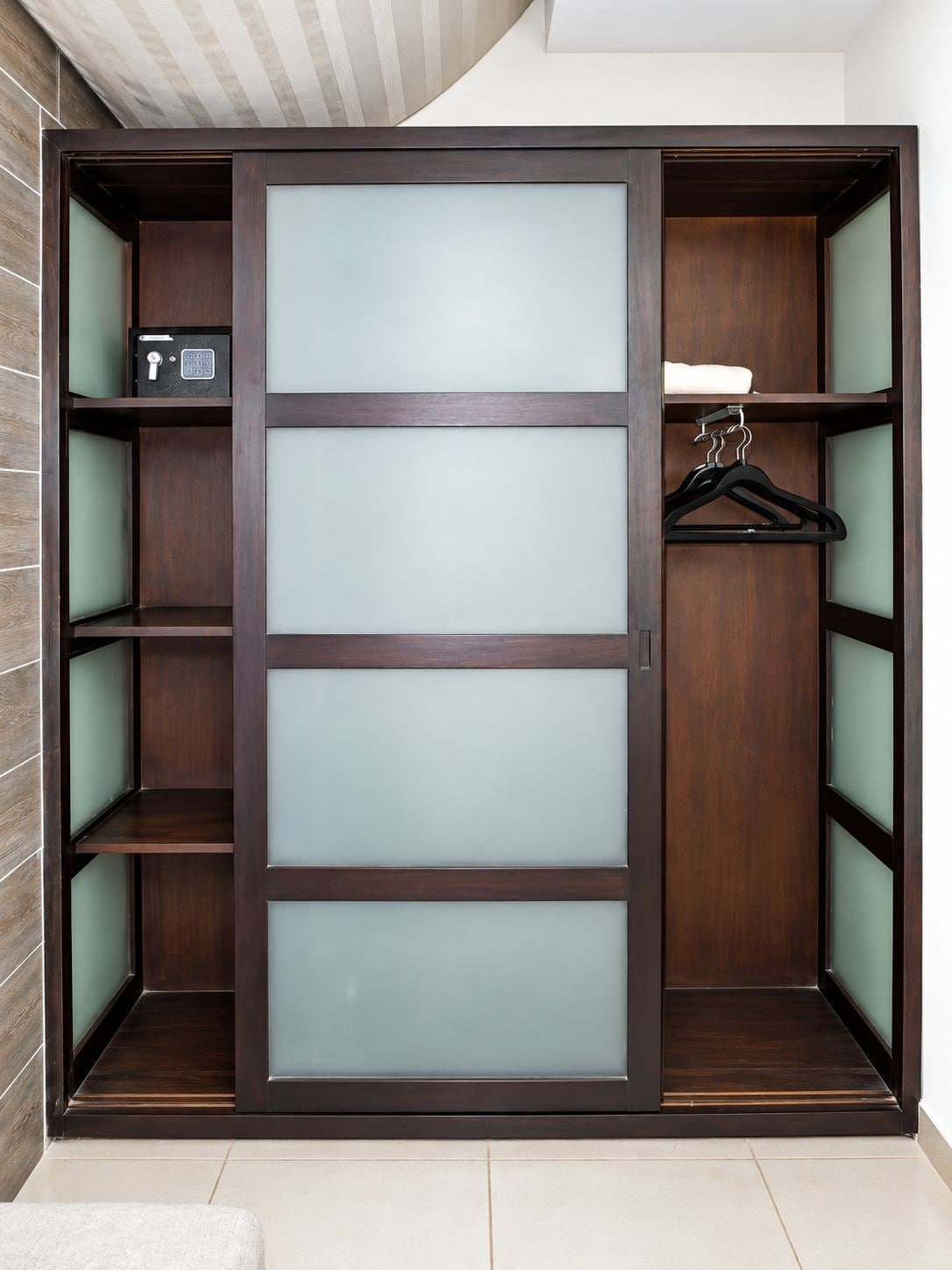 A walk-in closet with a large sliding door, multiple shelves, and a hanging rod.