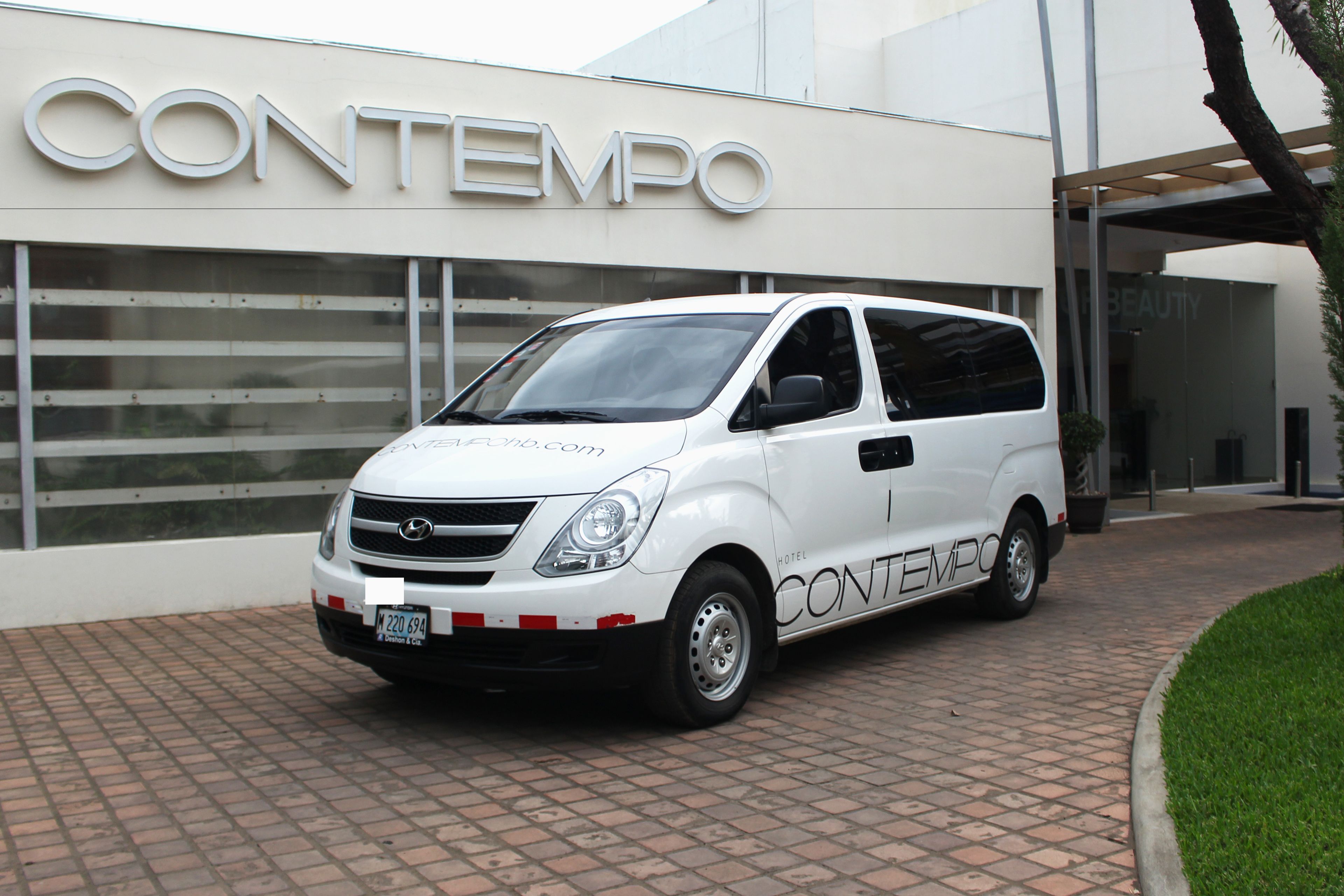 A white van parked in front of a building with the sign "CONTEMPO".
