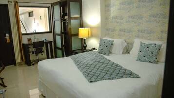 Une chambre d’hôtel comprenant un lit, un bureau avec une chaise, une lampe et un miroir.