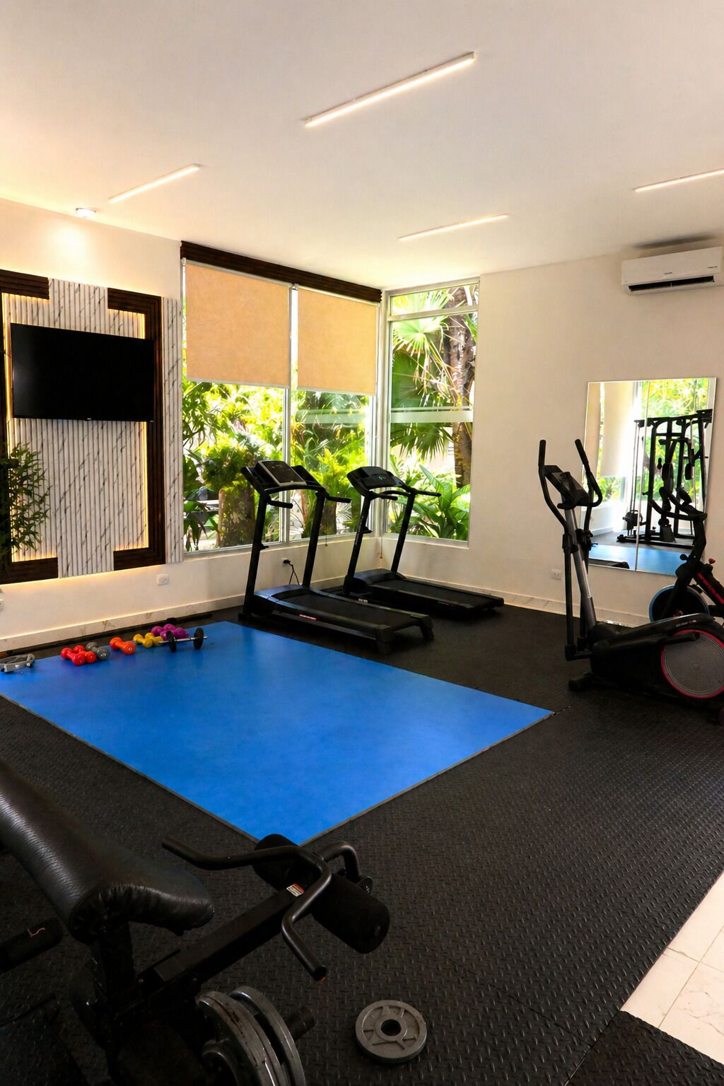 Ein Fitnessstudio mit Laufbändern, Crosstrainern und Gewichtsgeräten.