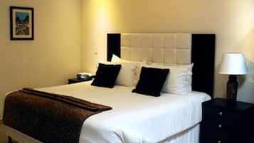 A neatly made bed with a brown blanket, a black nightstand with a lamp, and a framed picture on the wall.