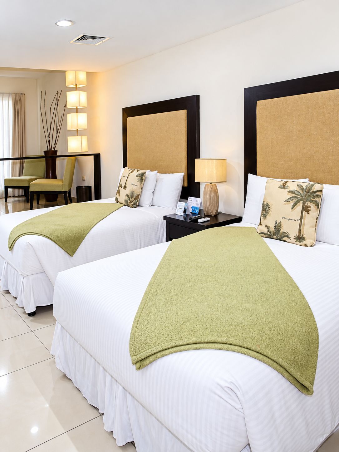 Habitación de hotel con dos camas, un escritorio, una silla y una lámpara.