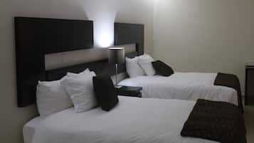 A hotel room with two beds, a headboard, a bedside table, and a lamp.