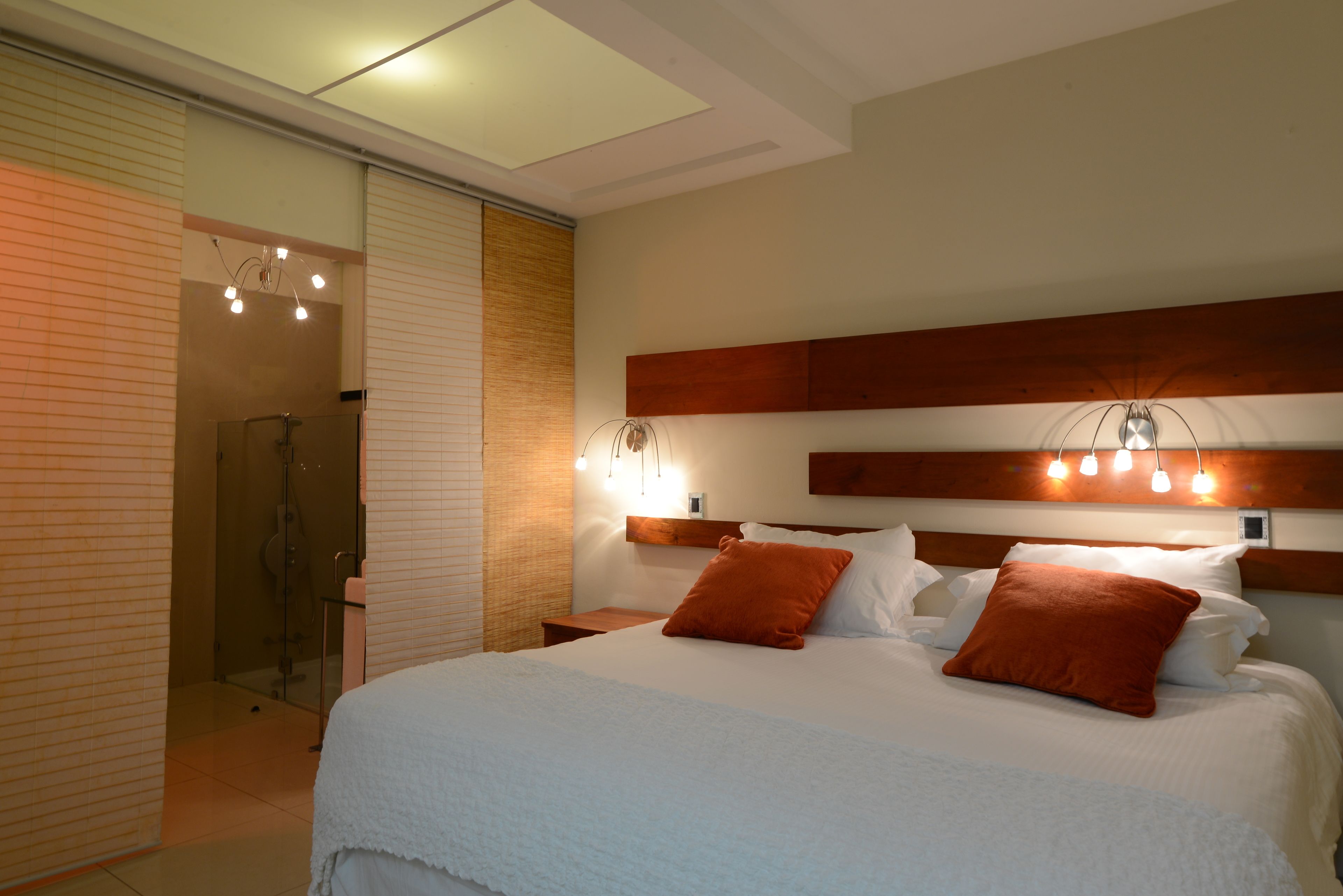 Une chambre moderne avec un grand lit, une tête de lit en bois et des lampes de chevet.