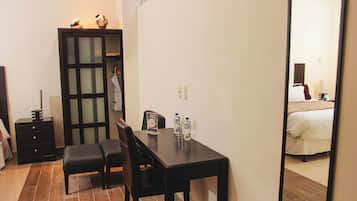 A hotel room with a bed, a desk with chairs, a wardrobe, and a mirror.