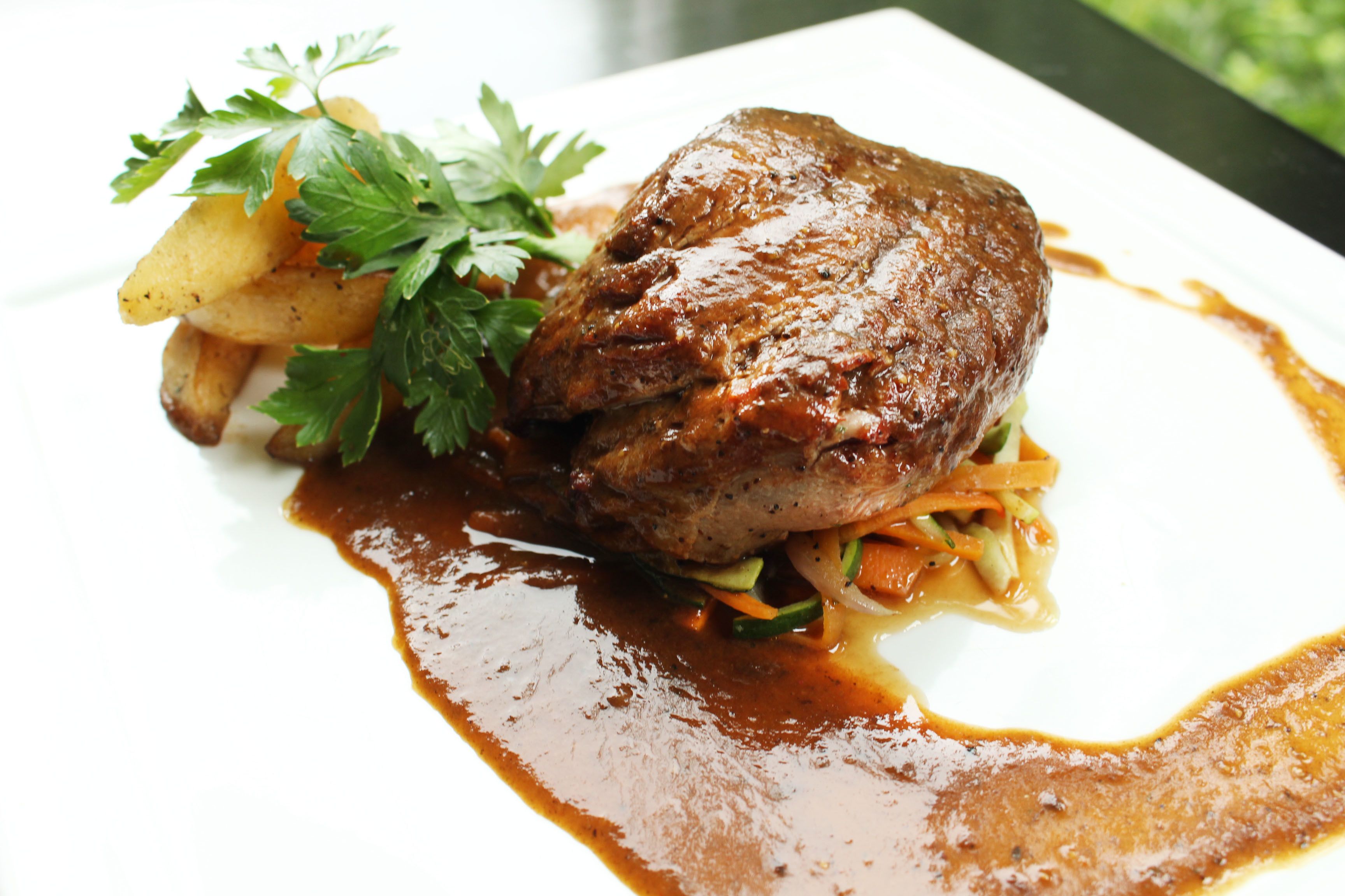 A plated dish with meat, vegetables, and a sauce.