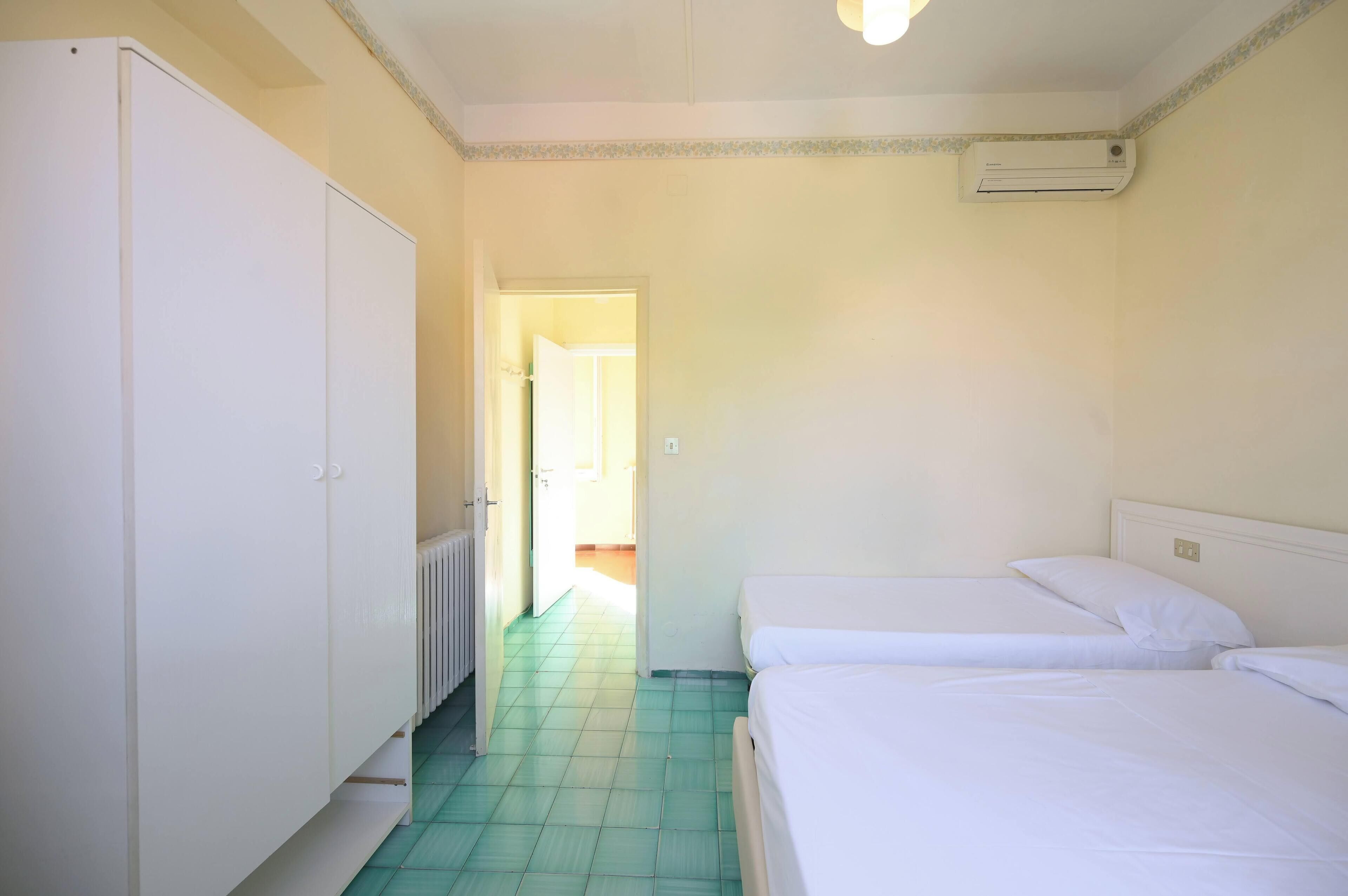 Une chambre avec deux lits, une armoire et un radiateur.