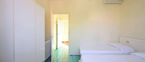Une chambre avec deux lits, une armoire et un radiateur.
