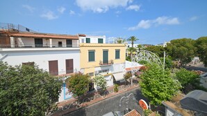 A street view with buildings, a Ferris wheel, and trees. - Hotel Villa Diana (Ischia)