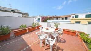 A rooftop patio with a round table and chairs, surrounded by potted plants. - Hotel Villa Diana (Ischia)