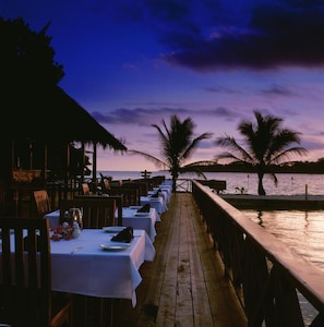Un restaurante frente al mar, con mesas dispuestas para comer, con vistas al océano.