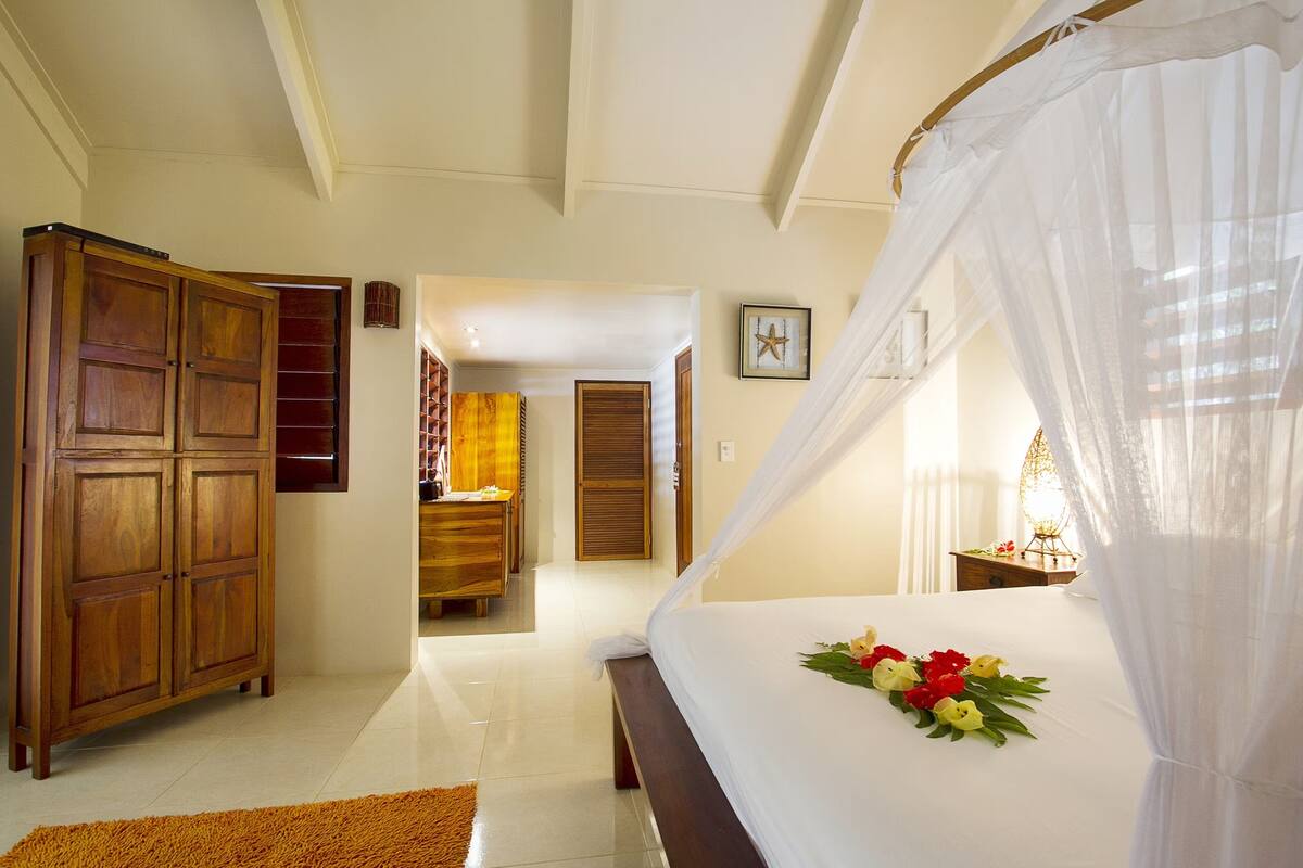 Een slaapkamer met een bed, een kledingkast en een badkamer op de achtergrond.