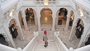A grand staircase with ornate white railings and a person descending.