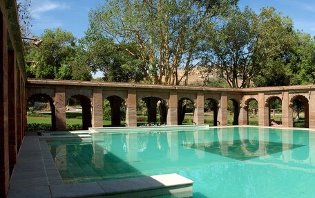 A pool with a series of arches and a clear blue sky in the background.