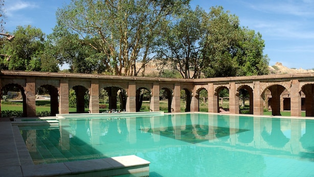 A pool with a series of arches and a clear blue sky in the background.