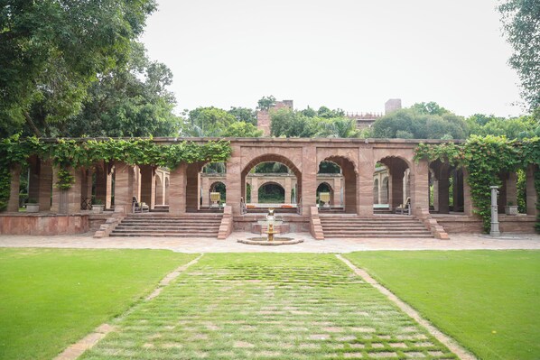A historic building with arched walkways and a central fountain. - WelcomHeritage Bal Samand Lake Palace (Jodhpur)