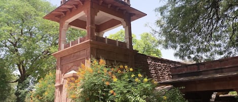 A stone structure with a covered upper section, surrounded by lush greenery and flowering plants.