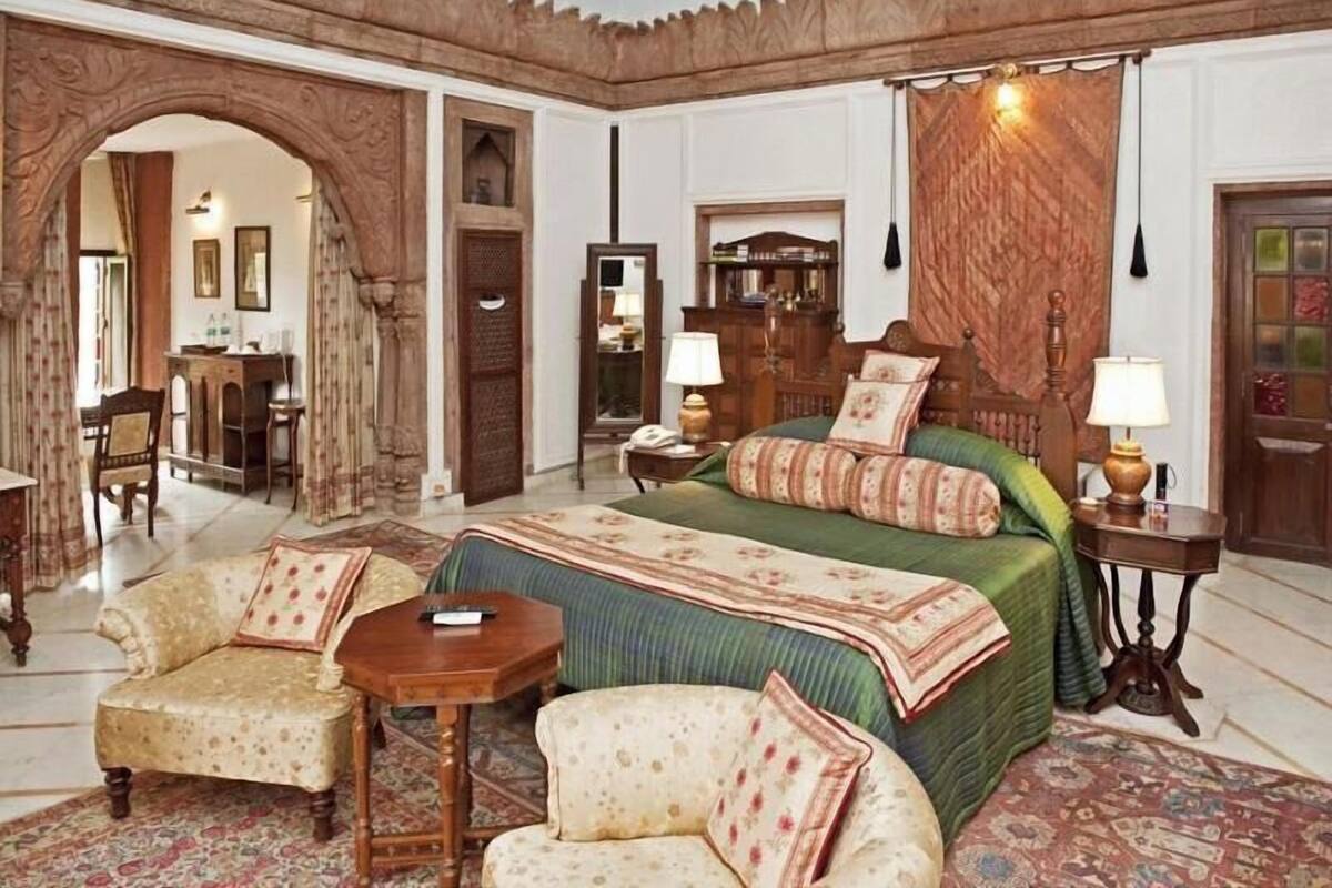 Ein Zimmer mit einem großen Bett, zwei Stühlen, einem kleinen Tisch und einem Kleiderschrank.