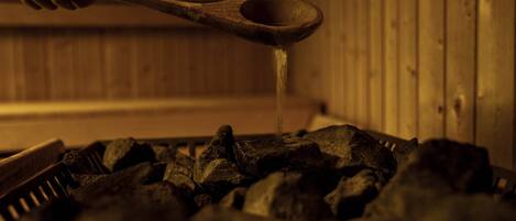A wooden spoon pouring liquid over charcoal.