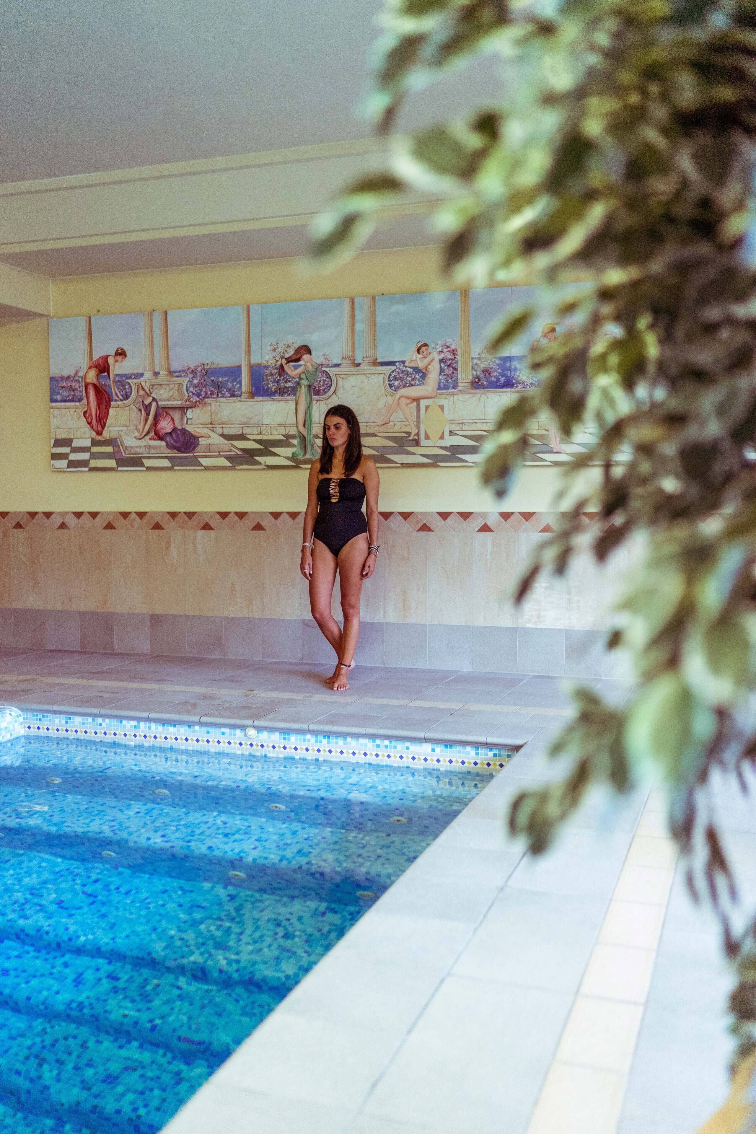 A pool area with a tiled floor and a person standing by the pool.