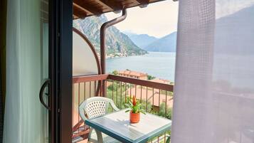 Ein Balkon mit Tisch und Stuhl, mit Blick auf einen See und Berge.