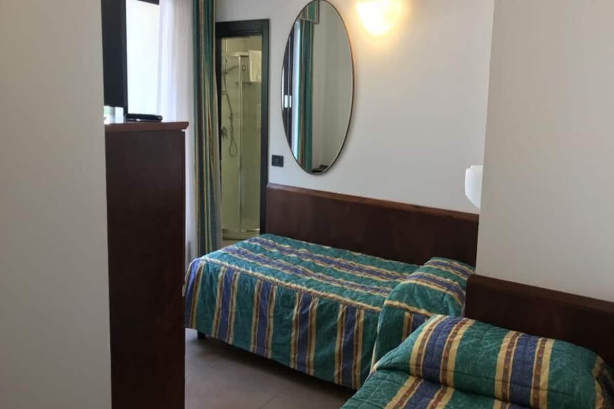 A bedroom with a bed, a wooden headboard, a mirror, and a door leading to a bathroom.