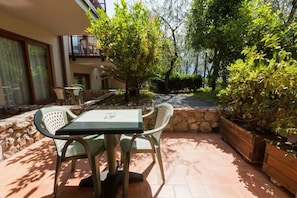 Une terrasse avec une table et des chaises, entourée de murs en pierre et de verdure.