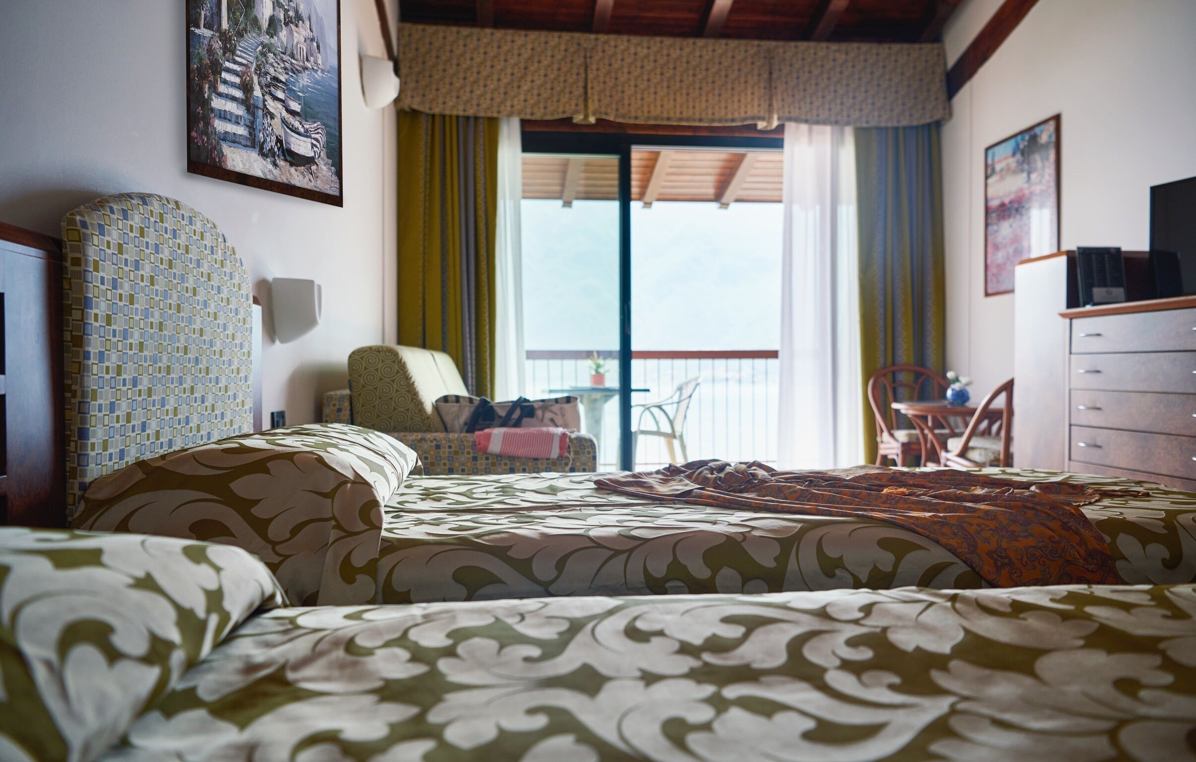 Een hotelkamer met een groot bed, een stoel, een bureau en een balkon met uitzicht.