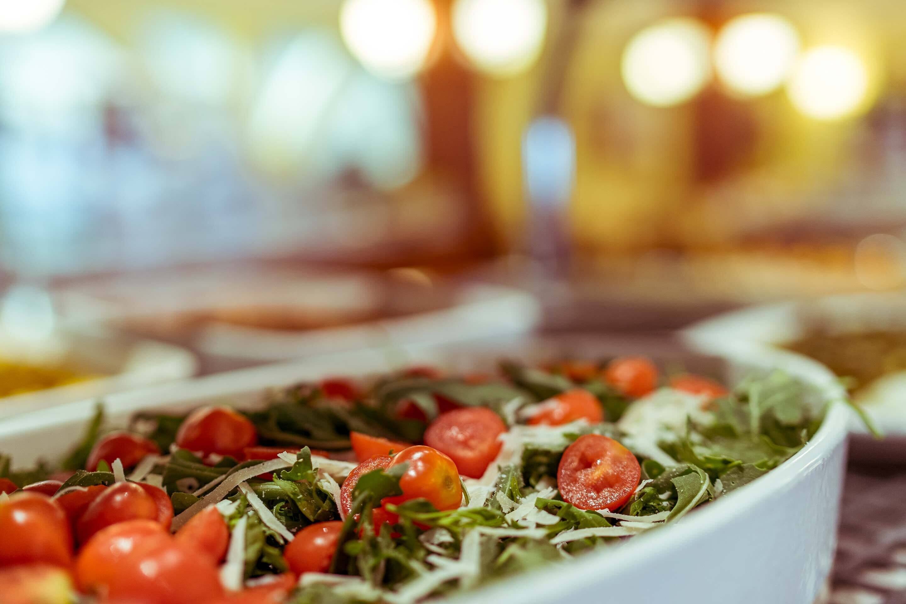 A bowl of salad with cherry tomatoes and greens.