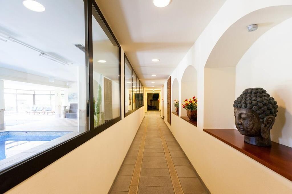 A corridor with a pool view, a Buddha statue, and a tiled floor.