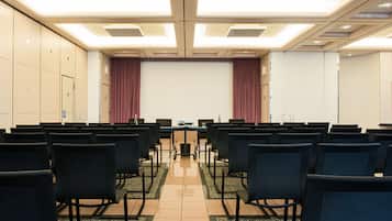 A seminar room with rows of chairs, a podium, and a large screen at the front.