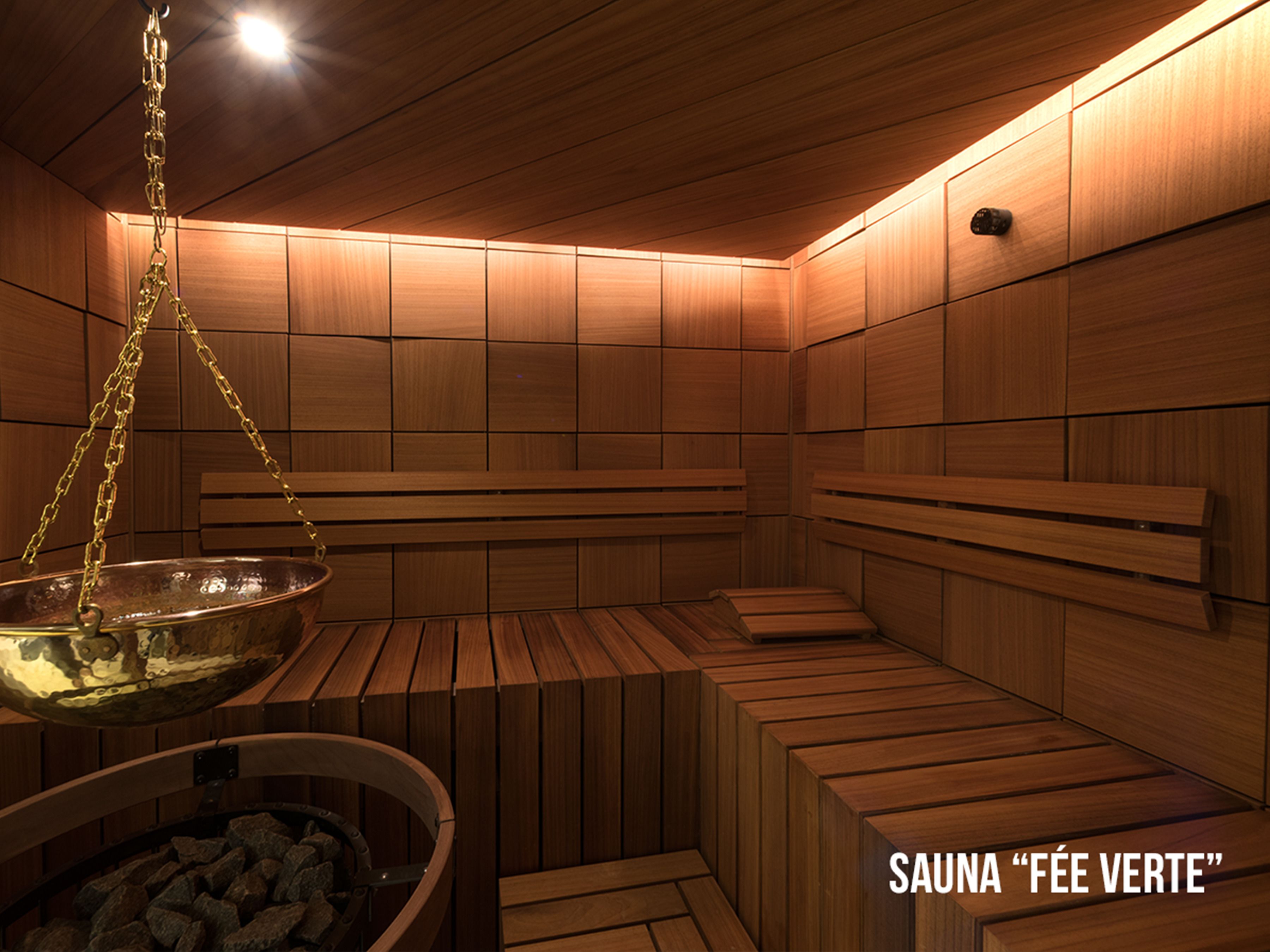 A sauna with wooden benches and a large metal basin filled with stones.