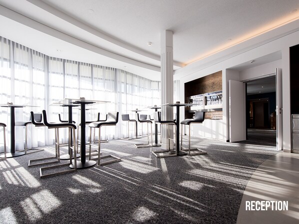 A modern reception area with a series of tables and chairs arranged for guests.
