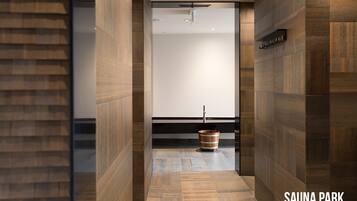 A modern sauna area with wooden walls and a wooden floor, a sauna bench, and a sauna heater.