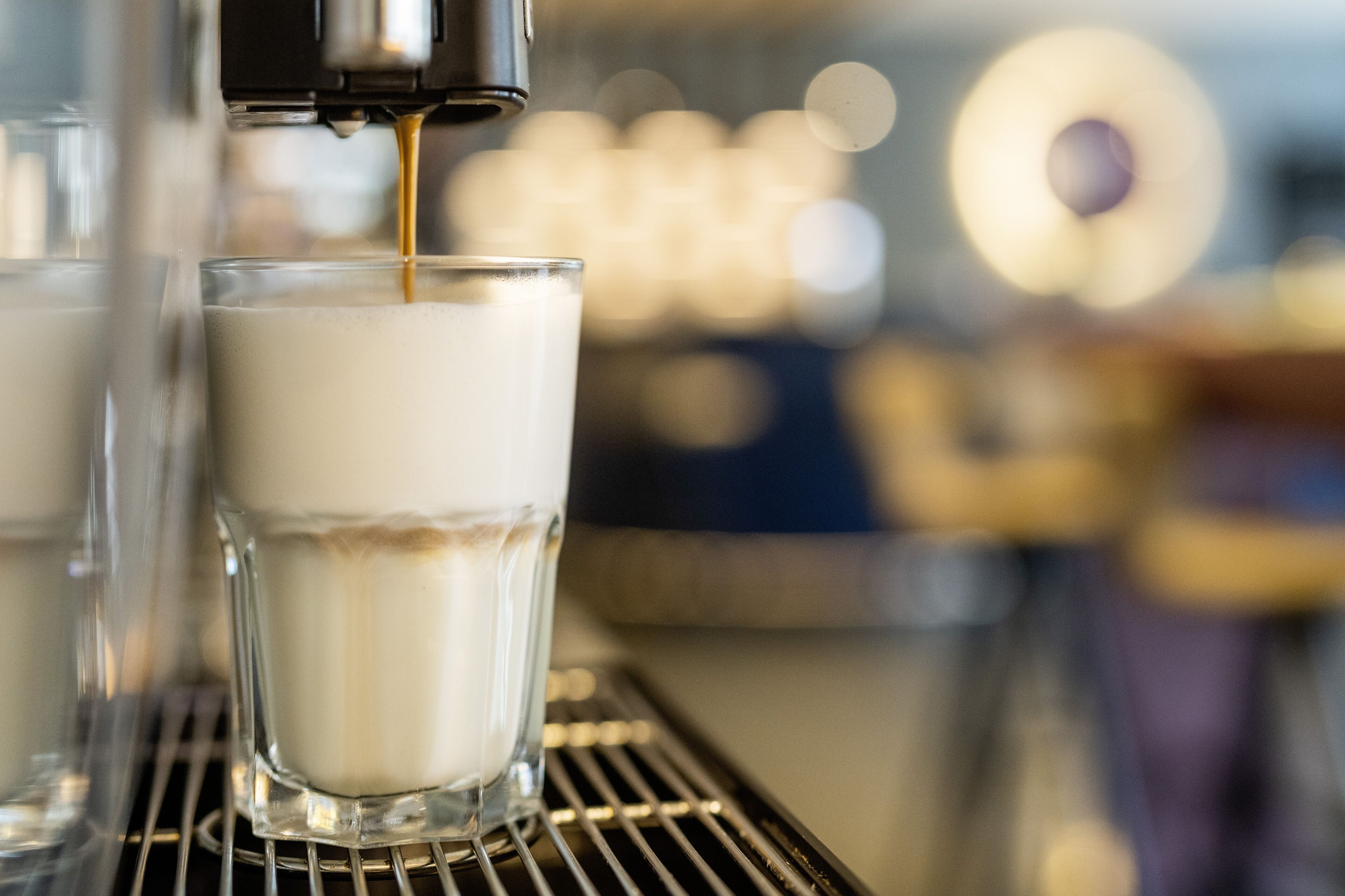 Gros plan sur une machine à café qui verse un expresso dans un verre.