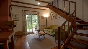Un salon chaleureux avec un escalier en bois, un canapé, une table basse et une grande fenêtre avec des rideaux.