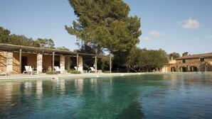 A swimming pool with lounge chairs and a covered seating area. - Hotel Rural Son Bernadinet (Campos)
