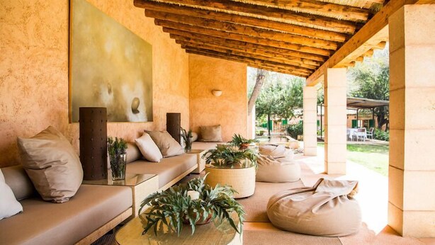A cozy, well-lit lounge area with a wooden ceiling, comfortable seating, and a large painting on the wall. - Hotel Rural Son Bernadinet (Campos)