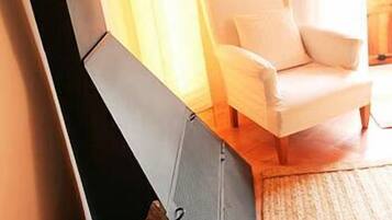 Una habitación con un sillón blanco, suelo de madera y un ventanal con cortinas.