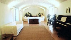 A living room with a sofa, a coffee table, a piano, and a fireplace. - Hotel Rural Son Bernadinet (Campos)