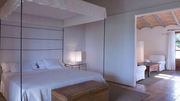 Un dormitorio con una cama grande, mesitas de noche, un cofre de madera y una silla.