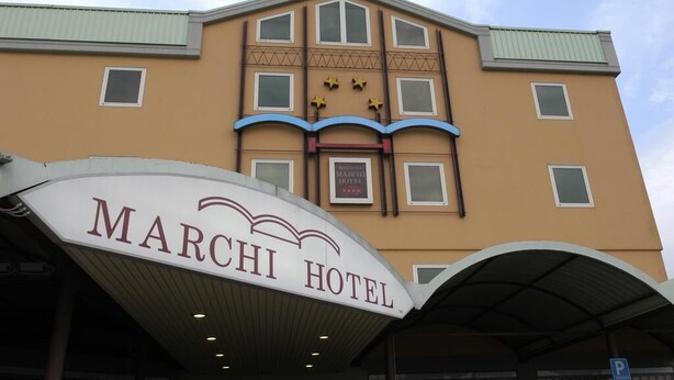The exterior of the Marchi Hotel with a prominent sign, multiple windows, and a covered entrance area. - Marchi (Soliera)