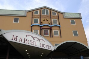 The exterior of the Marchi Hotel with a prominent sign, multiple windows, and a covered entrance area. - Marchi (Soliera)