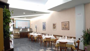 A restaurant with tables set for dining, a bar area, and framed artwork on the walls. - Marchi (Soliera)