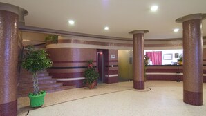 A spacious lobby with a marble floor, large columns, and potted plants. - Marchi (Soliera)