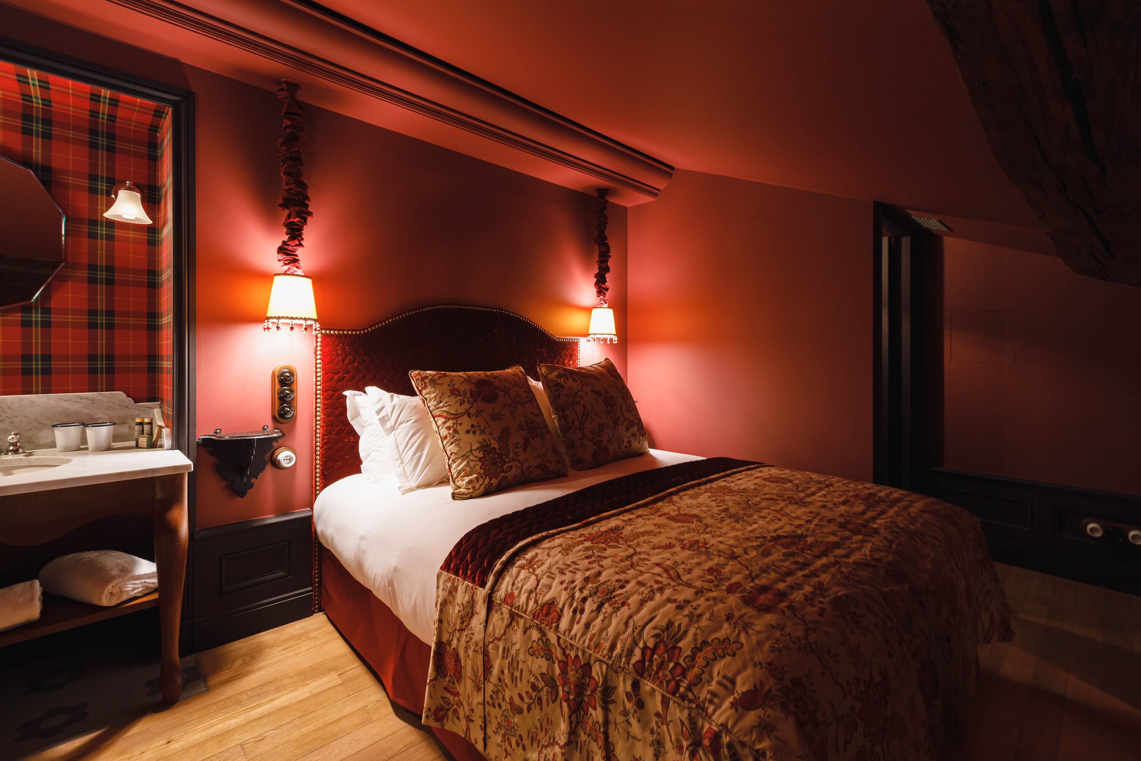 Una habitación con una cama, una mesita de noche, una lámpara y un espejo.